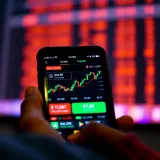 Mobile phone screen showing a stock trading app interface with graphs and stock prices